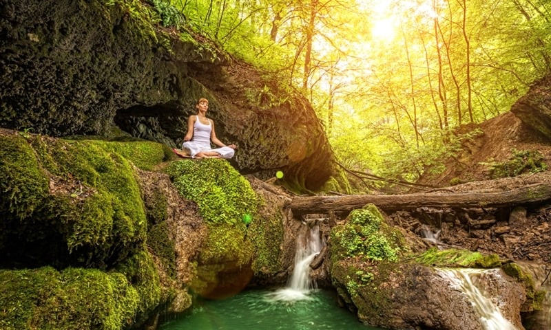 Relaxation in forest at the Waterfall. Ardha Padmasana pose.