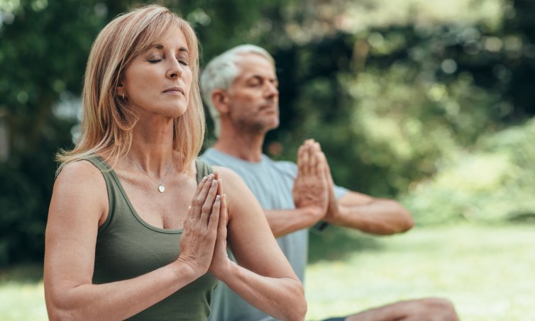 Mature couple meditating together during yoga practice outside Retiro Detox y Bienestar en la Sierra de Aracena