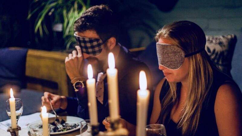 Cena sensorial a ciegas con antifaces y luz de velas, representando la experiencia mindful eating del Retiro de Perfumería Natural, Alta Cocina y Gongs en la Sierra de Aracena.