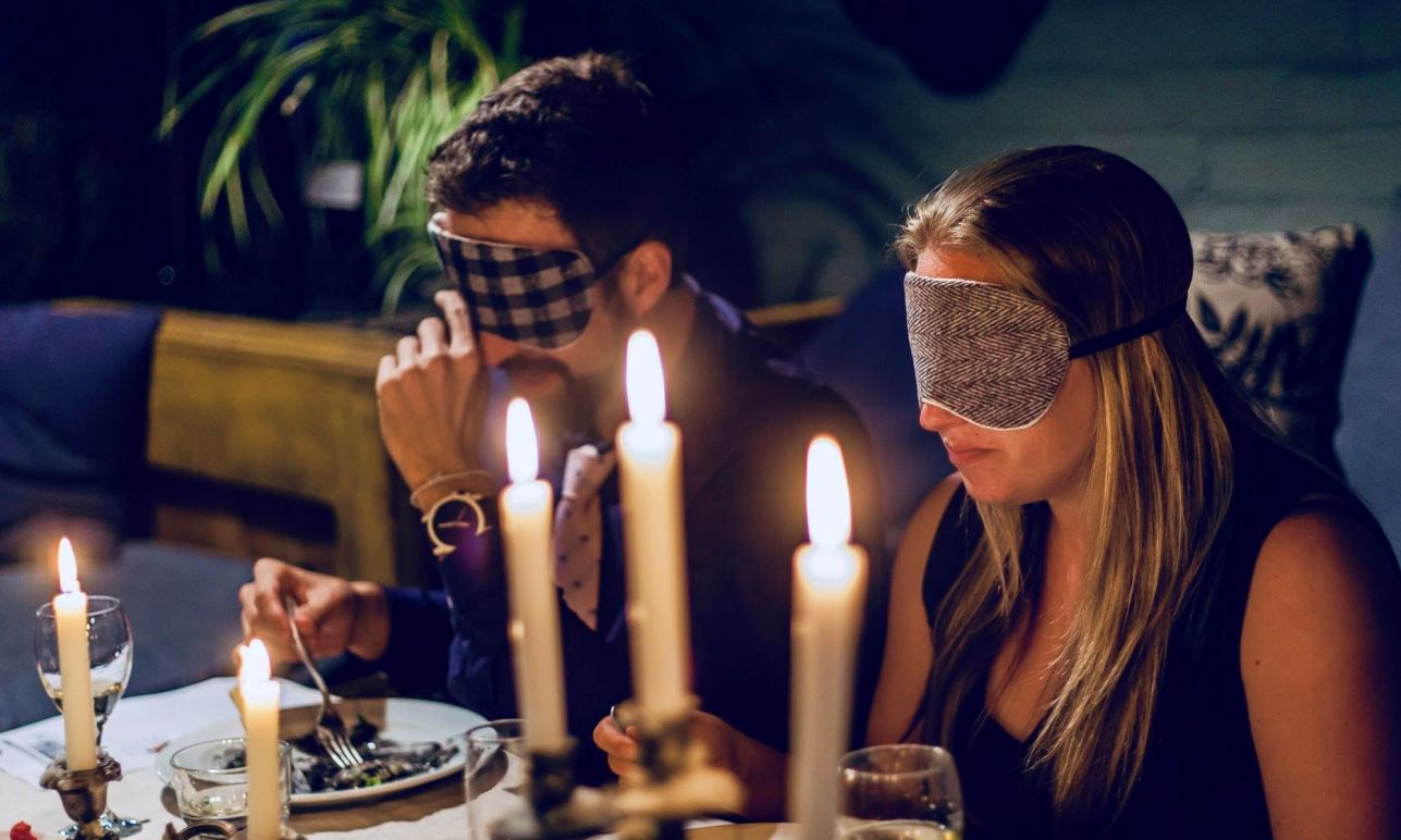 Cena sensorial a ciegas con antifaces y luz de velas, representando la experiencia mindful eating del Retiro de Perfumería Natural, Alta Cocina y Gongs en la Sierra de Aracena.