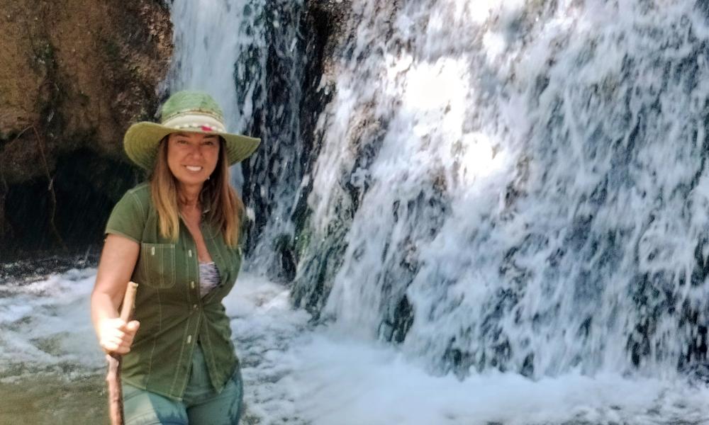 Elena junto a la Cascada de los Molinos, rodeada de vegetación en la Sierra de Aracena, un entorno natural único cerca de la Hospedería de la Corte.
