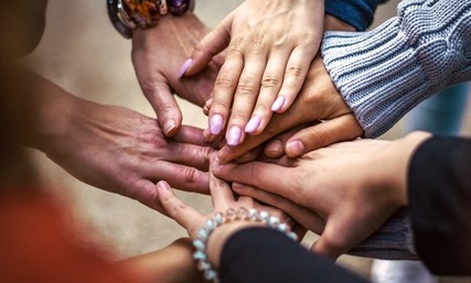 Manos unidas formando un equipo durante una dinámica de team building en la Hospedería de la Corte, Sierra de Aracena.